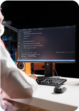 Person programmiert am Computer mit sichtbarem Code auf dem Bildschirm in dunkler Umgebung
