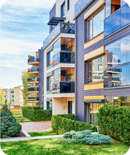 Moderne Mehrfamilienhäuser mit Balkonen und gepflegtem Garten bei klarem Himmel