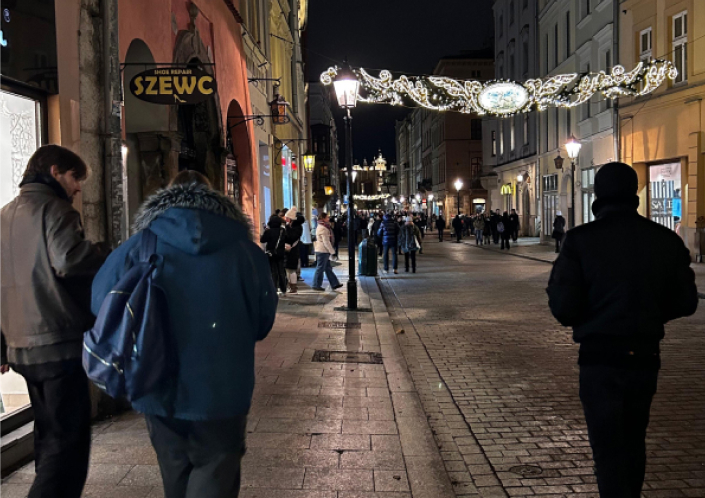 Nächtliche Straßenansicht mit Fußgängern, Lichterketten und Ladenfronten in einer Altstadt